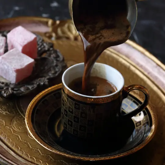 Turkish Coffee Pot pouring coffee into a  demitasse cup with Turkish Delight