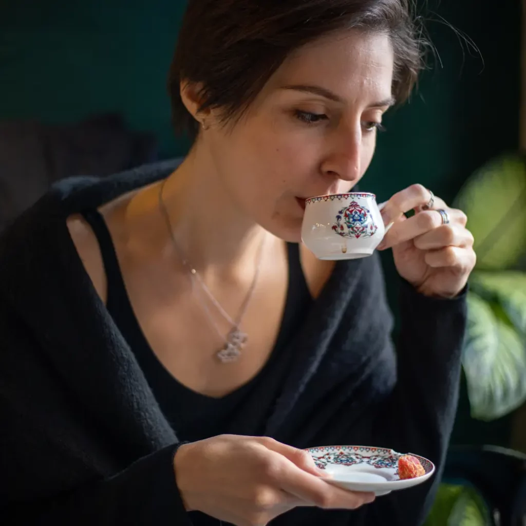 woman sipping from a traditional demitasse cup