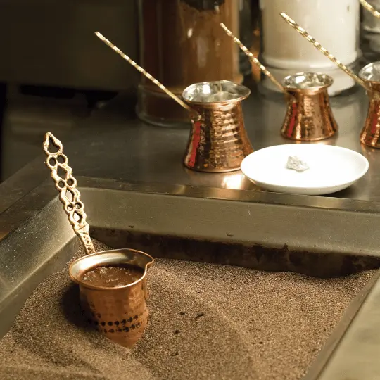 Pot brewing Turkish coffee in sand
